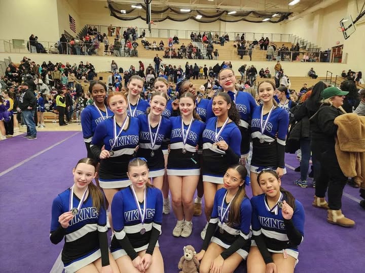 JV cheerleading team posing wearing silver medals.