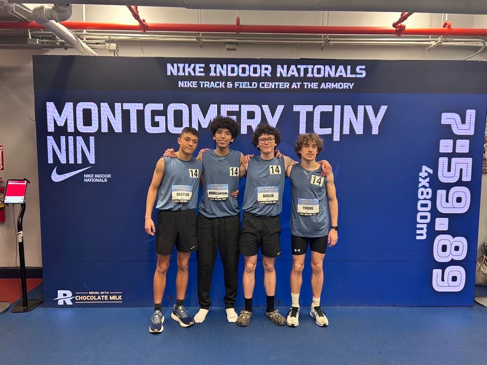 Four boys track members standing in front ofa backdrop that says Montgomery TCINY 7:59.89