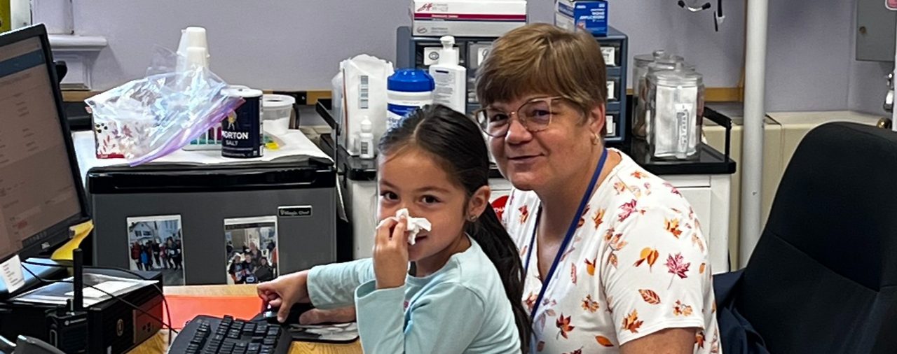Our WES LPN taking care of a little girl who is helping her out on the computer!