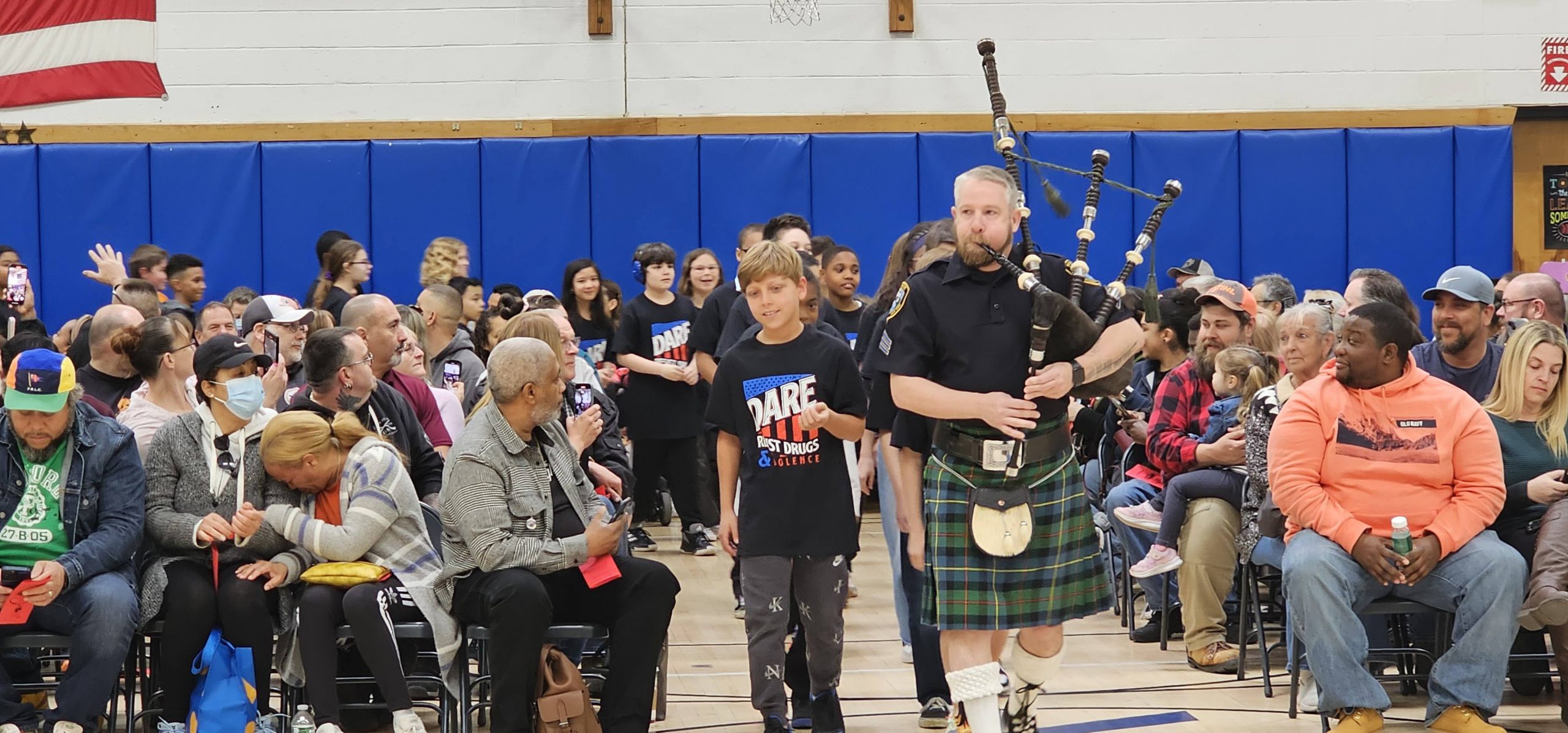 Berea DARE Graduates are led into their celebration with a bagpiper player.  The audience is on either side