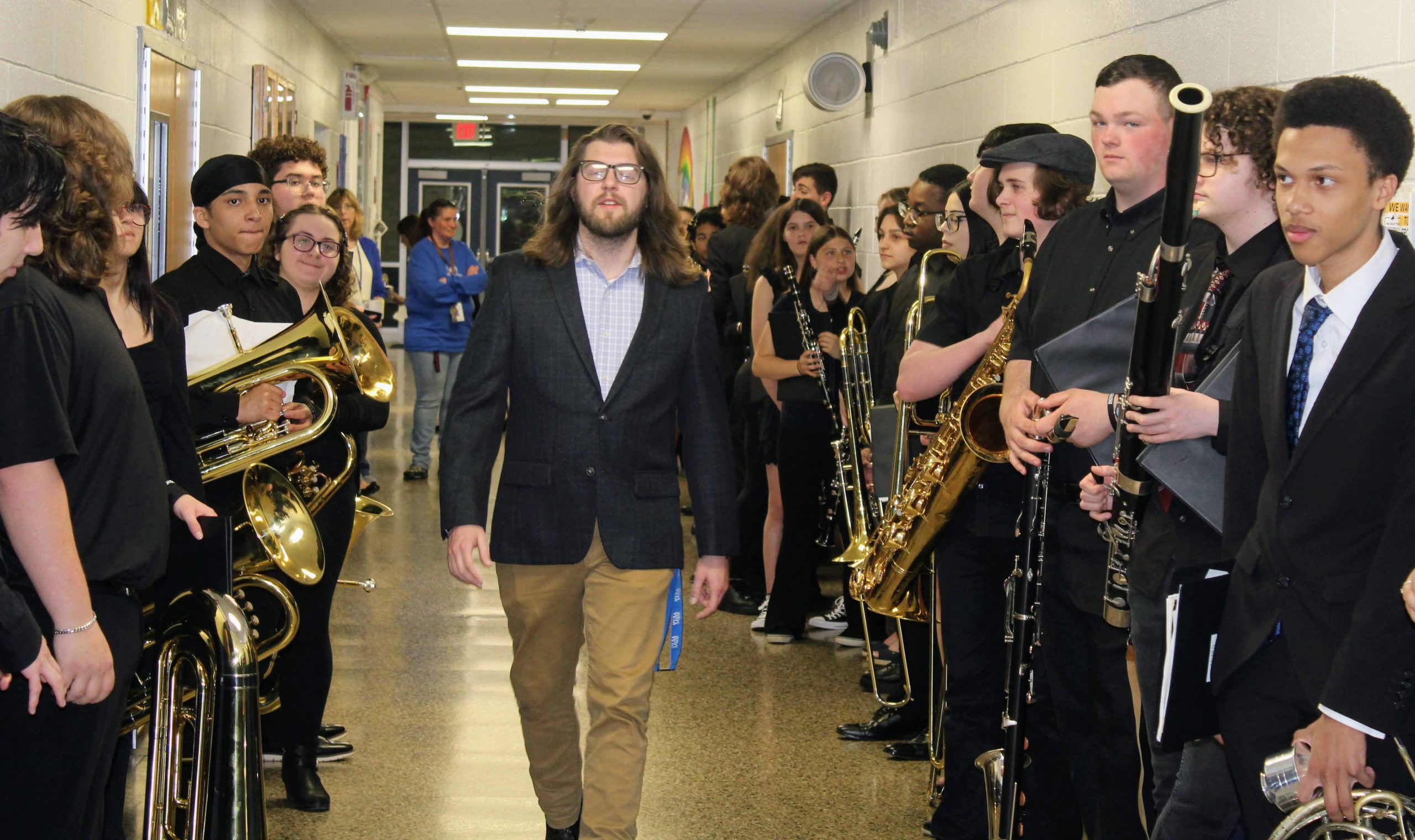 Music Teacher, Mr. Walker, strides down the hallway lined with band members on his way into the Spring concert