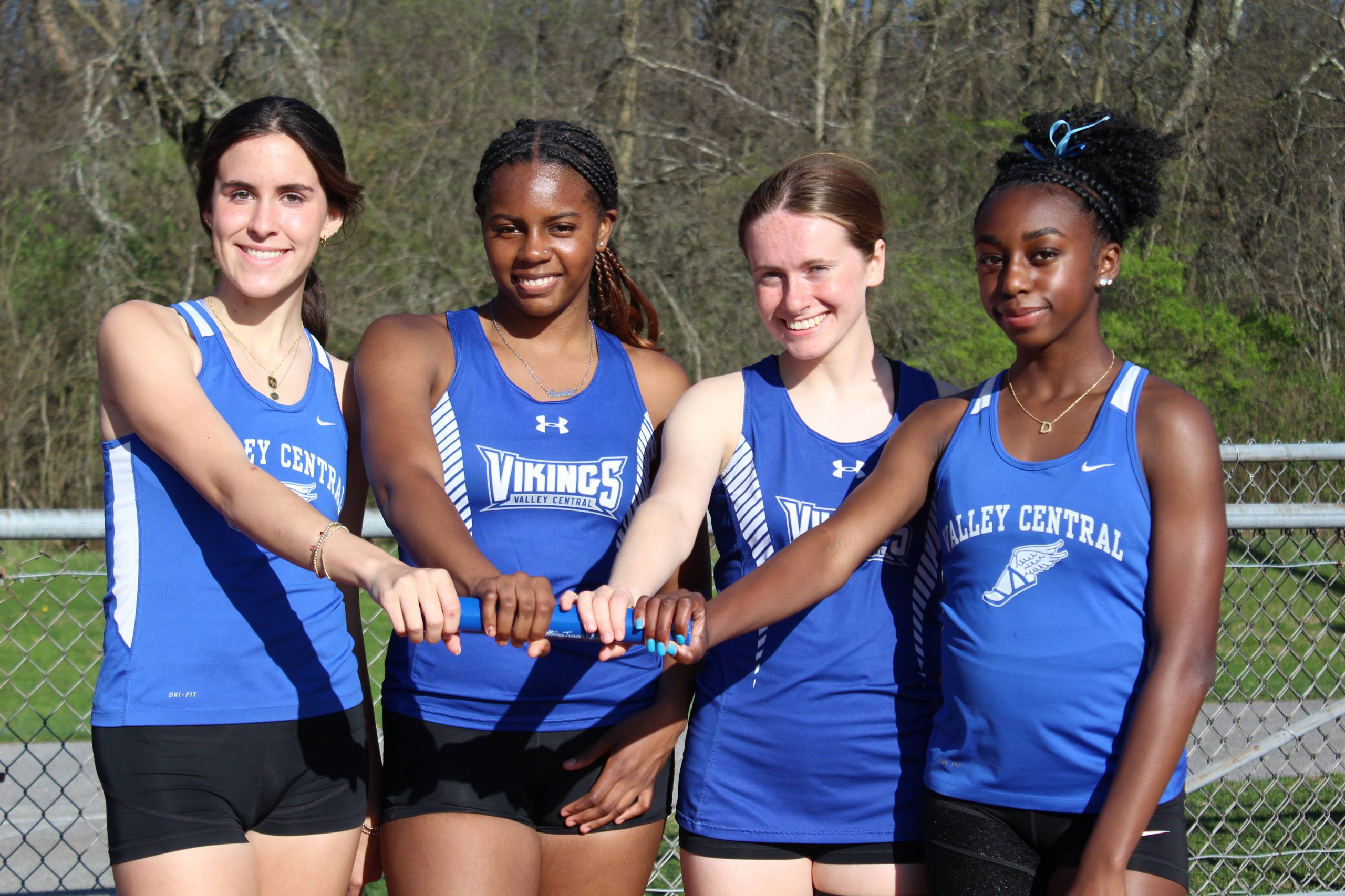 Four team members from the Girls Spring Track team take a moment to first bump before a meet.