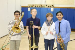 Four students with instruments smile for a photo