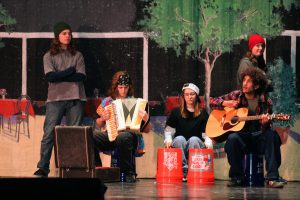 Students are sitting and playing instruments. 