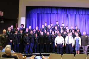 Students in the J.R.O.T.C. program stand for a group photo on stage at an event. 