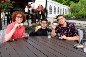 Three students hold up tea cups at the senior dinner.