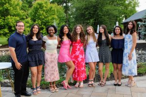 A group of students stands and smiles for a photo outside at the senior dinner. 