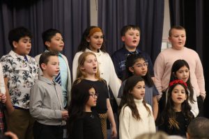 Students standing together and singing at a concert. 