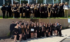 Two different groups of students wearing black are posing for a photo outside at Valley Central