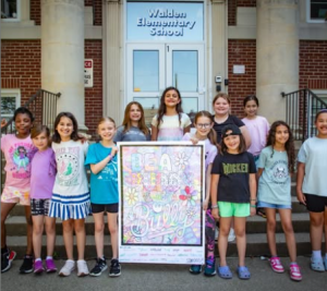 Students stand around a teacher that has artwork on display. 