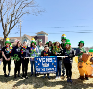 Students stand with a sign and leprechaun hats on. 