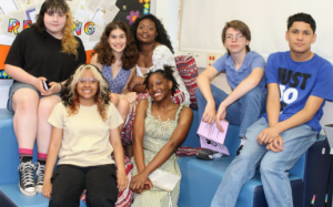 Students sit on a couch and look at the camera at the middle school recognition night. 