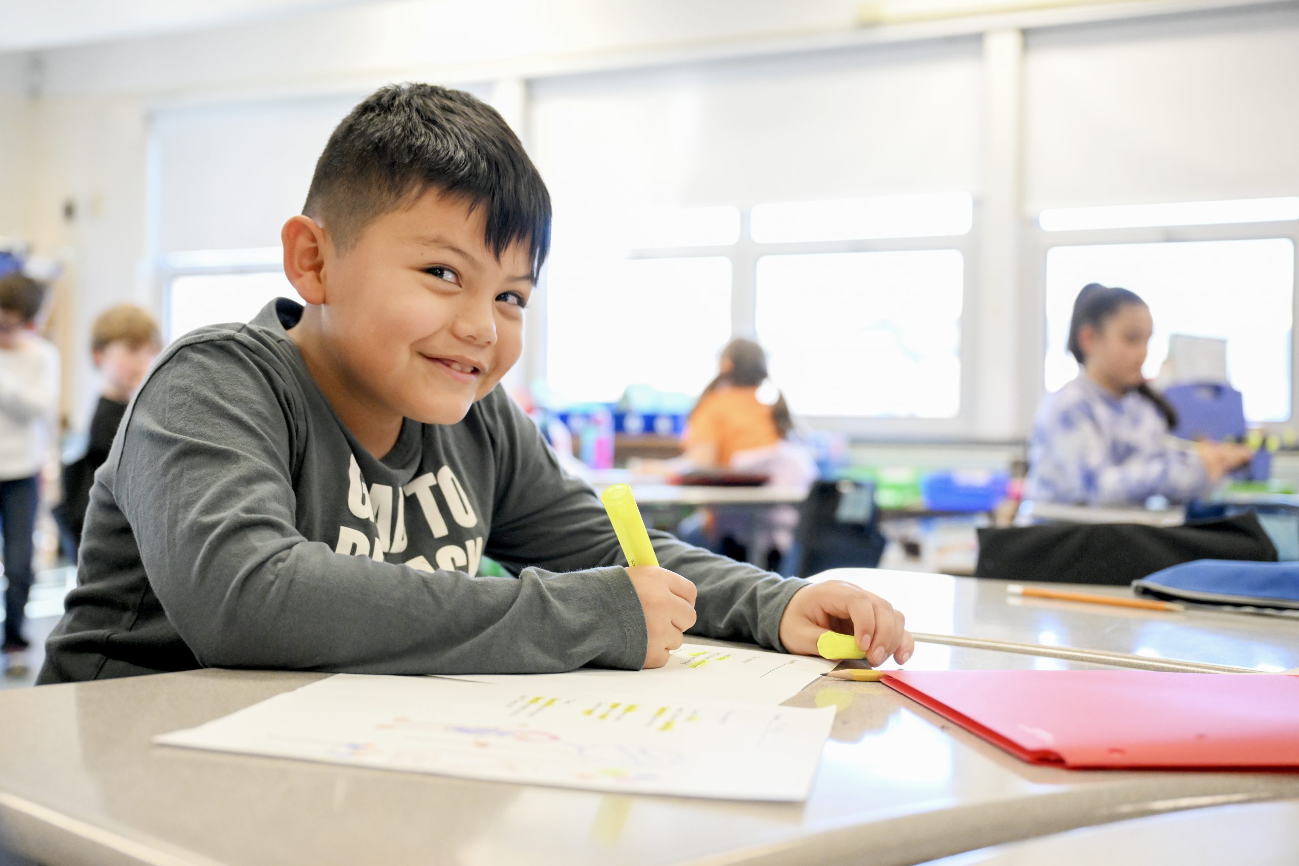 Student sitting at a desk holding a highlighter.