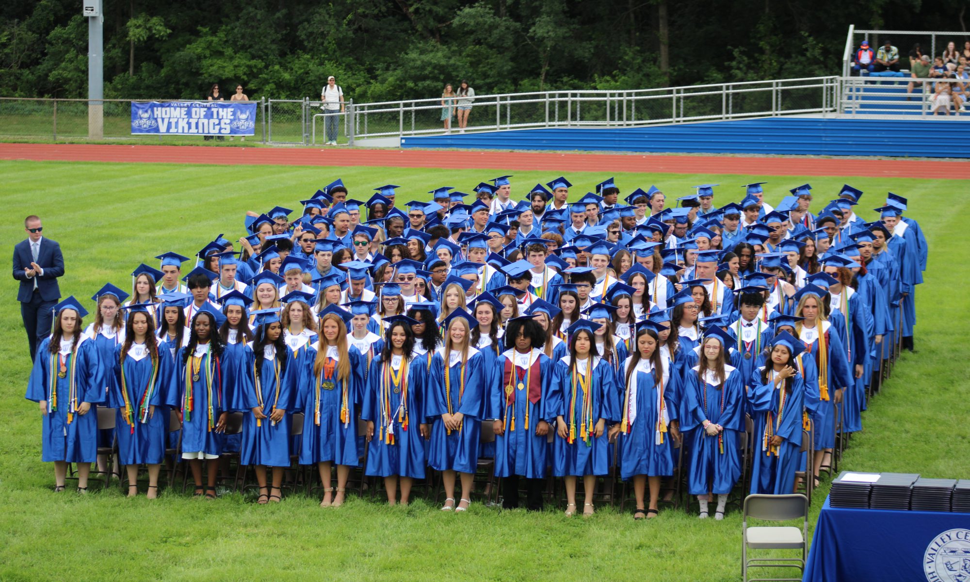 Graduating seniors are standing on the field during Valley Central's high school graduation.