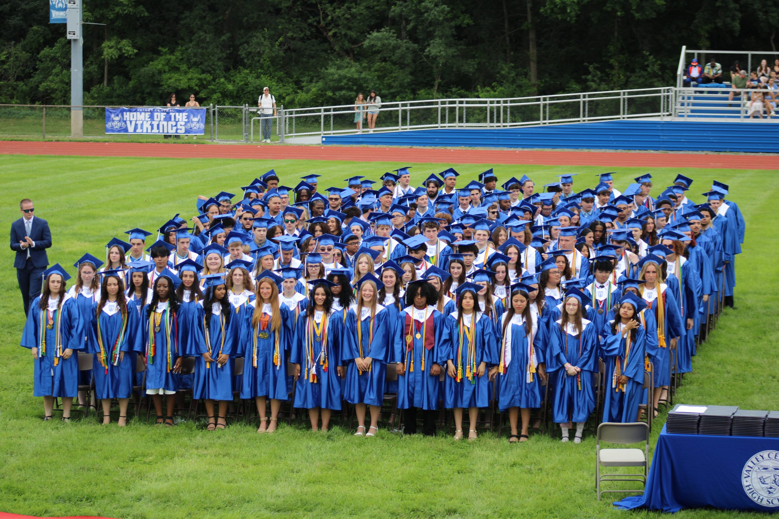 Graduating seniors are standing on the field during Valley Central's high school graduation. 