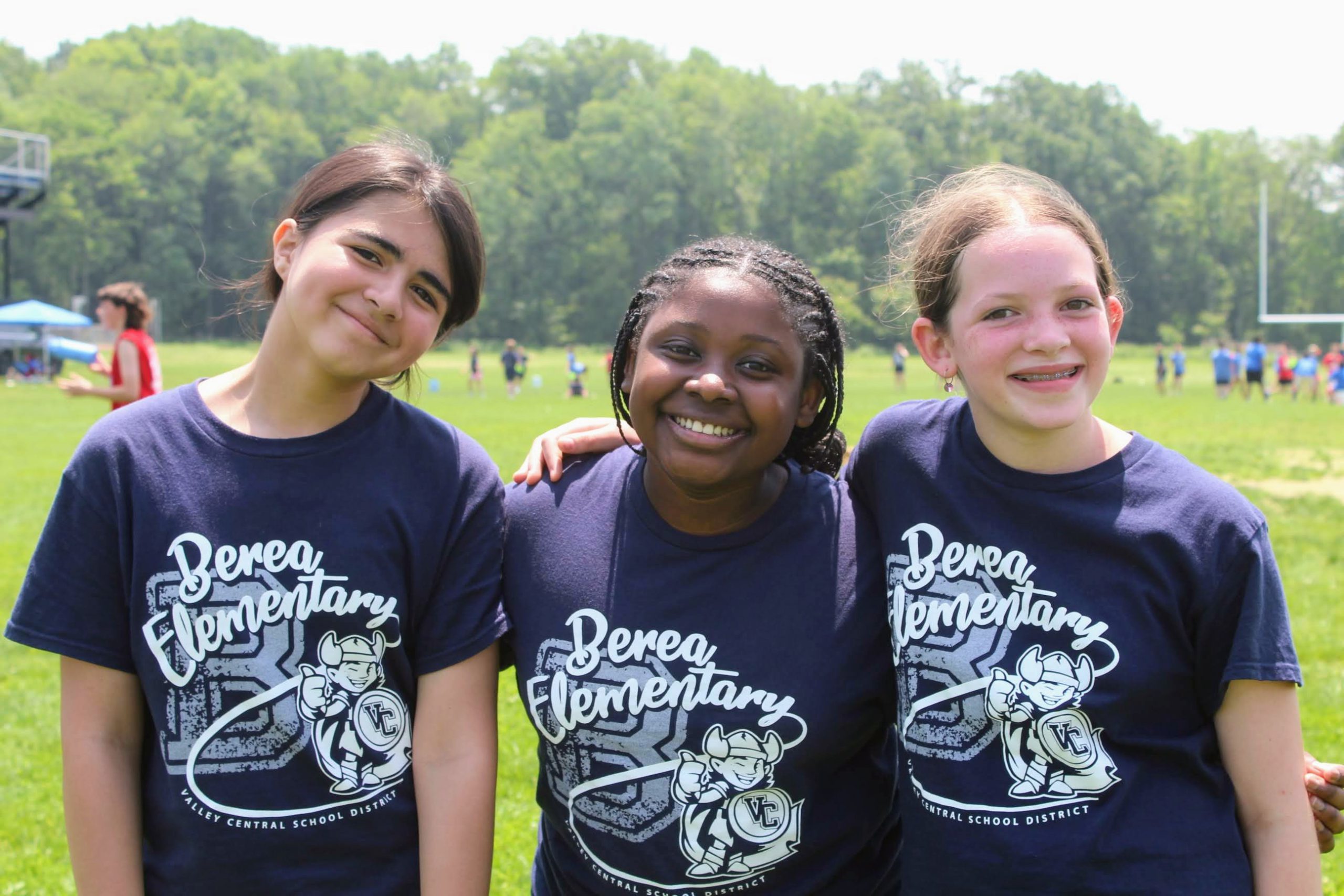 Three girls stand and smile at the camera in their Berea elementary school shirts at field day. 