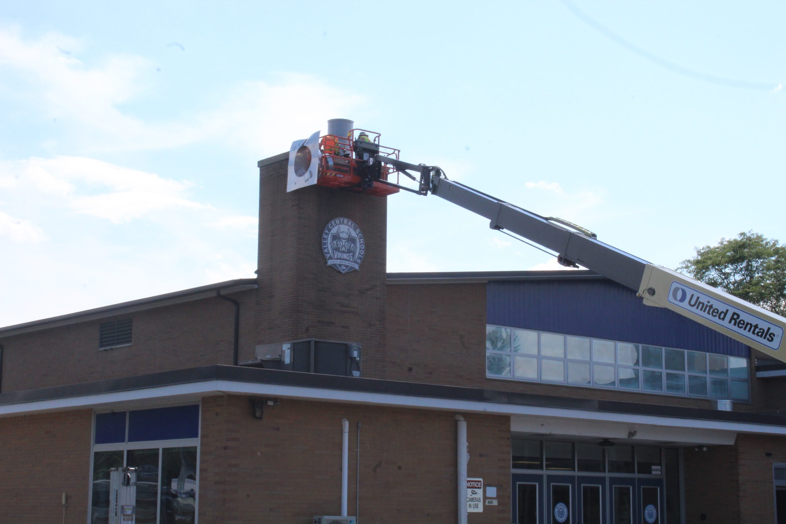 A construction worker is in a crane at the top of Valley Central high school