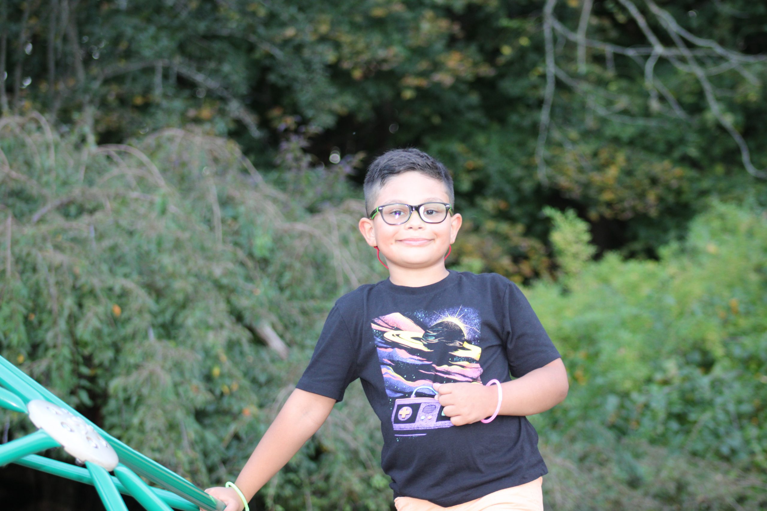 Student at MES smiling at the top of the jungle gym.