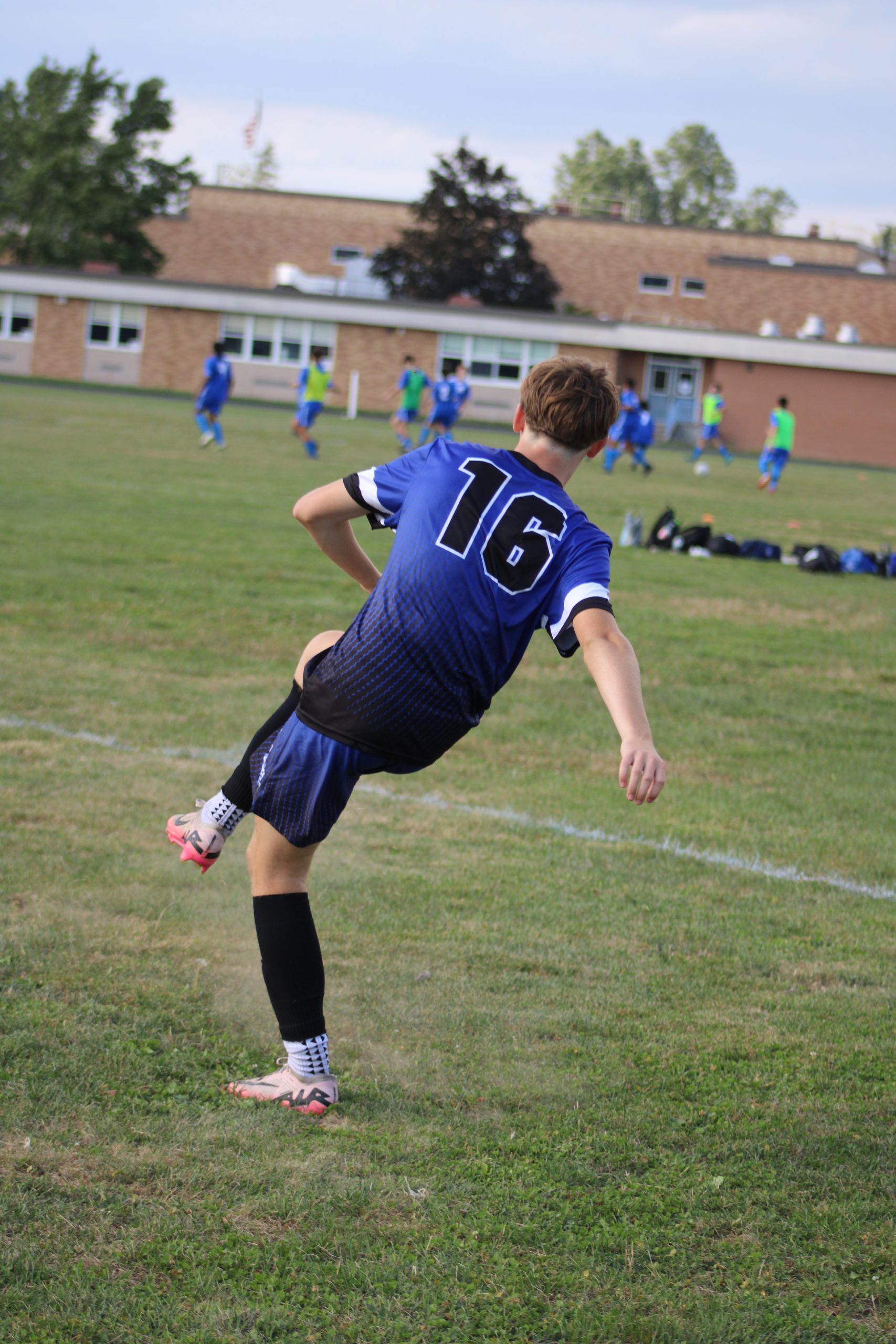 Boy with back to camera kicking a soccer ball.