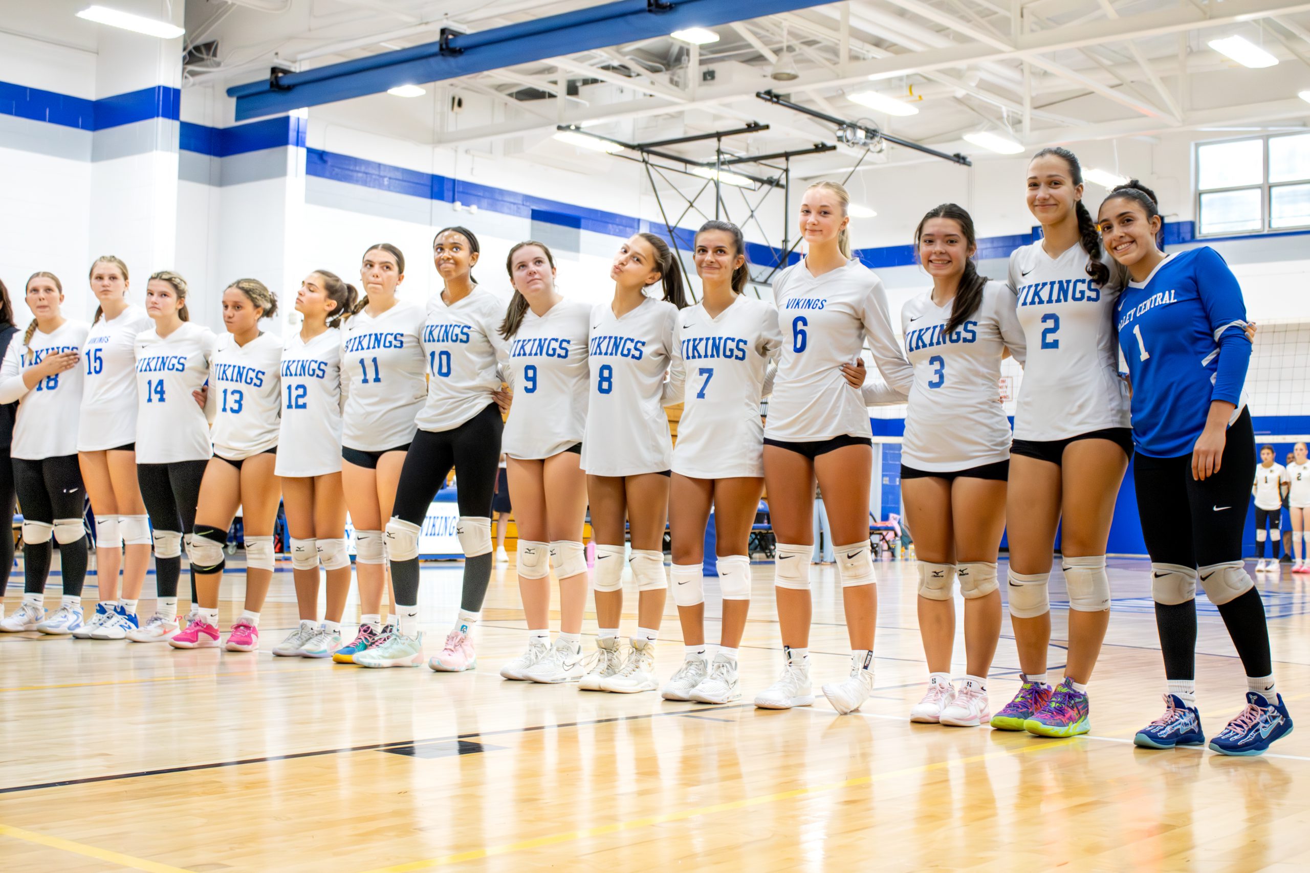 Group of volleyball players standing in a line in uniform.
