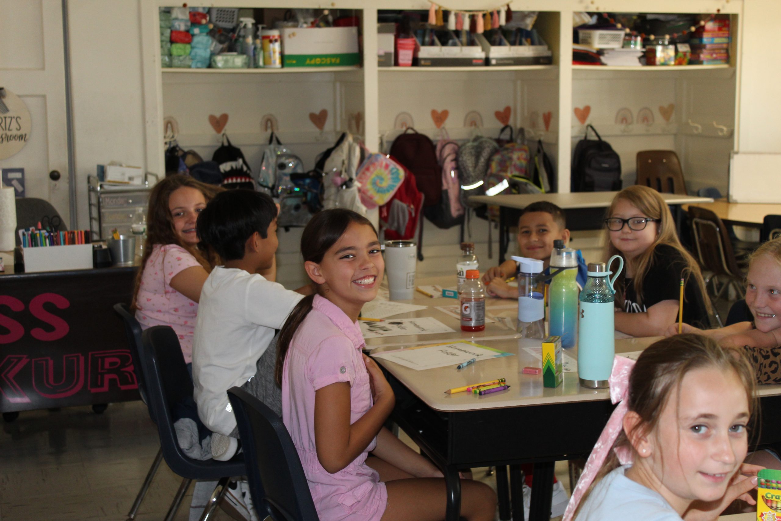 Students turn and look at the camera and smile on the first day of school. 