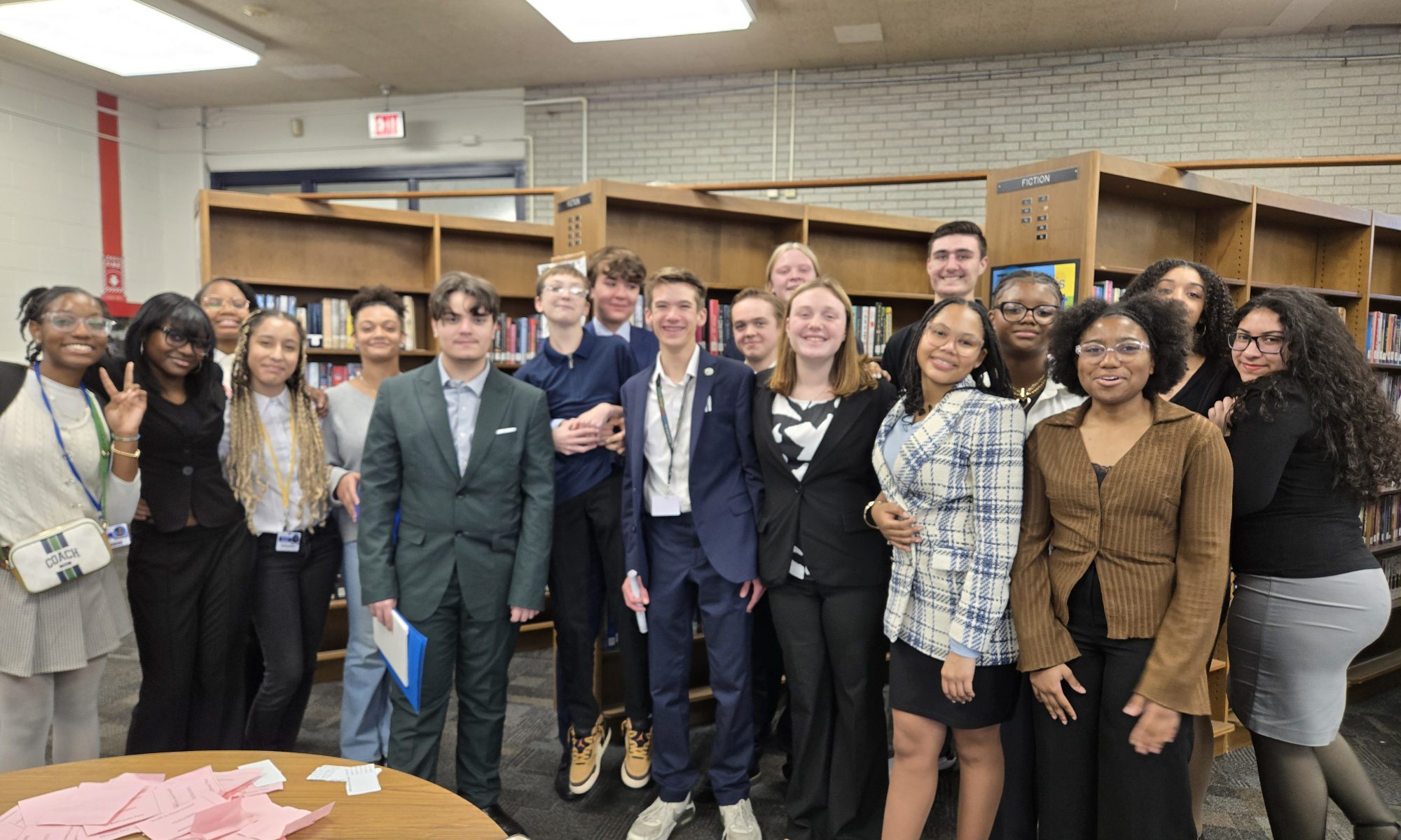 Group of students dressed in suites posing in a library.