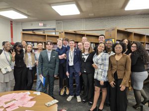 Group of students dressed in suites posing in a library.