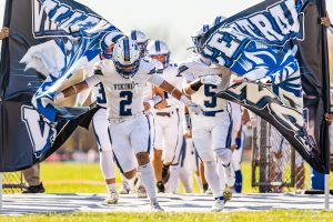 VC football players running through their Viking banner.
