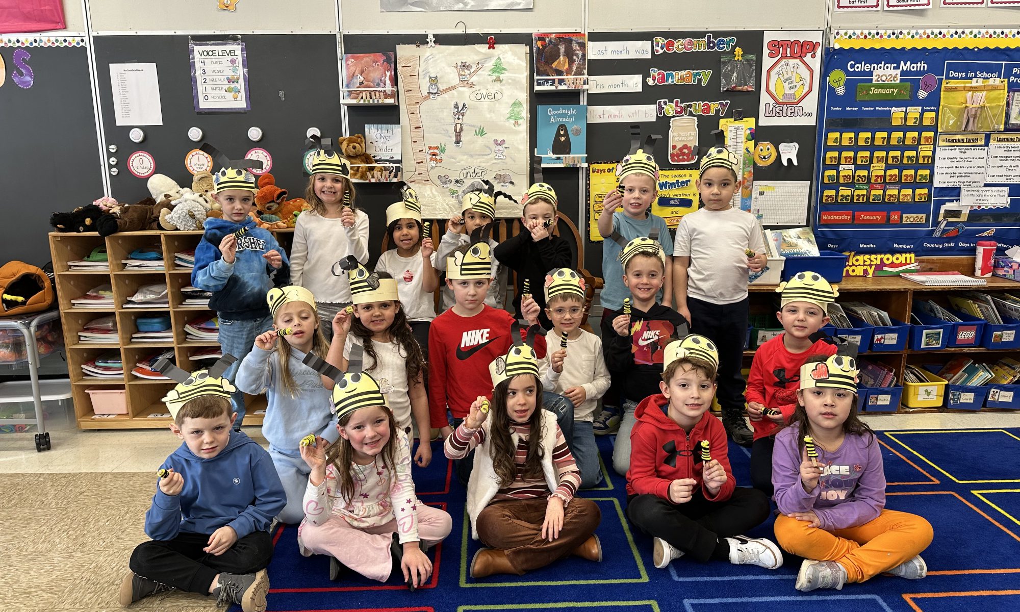 Large group of kindergarteners posing in a group wearing paper hats they made.