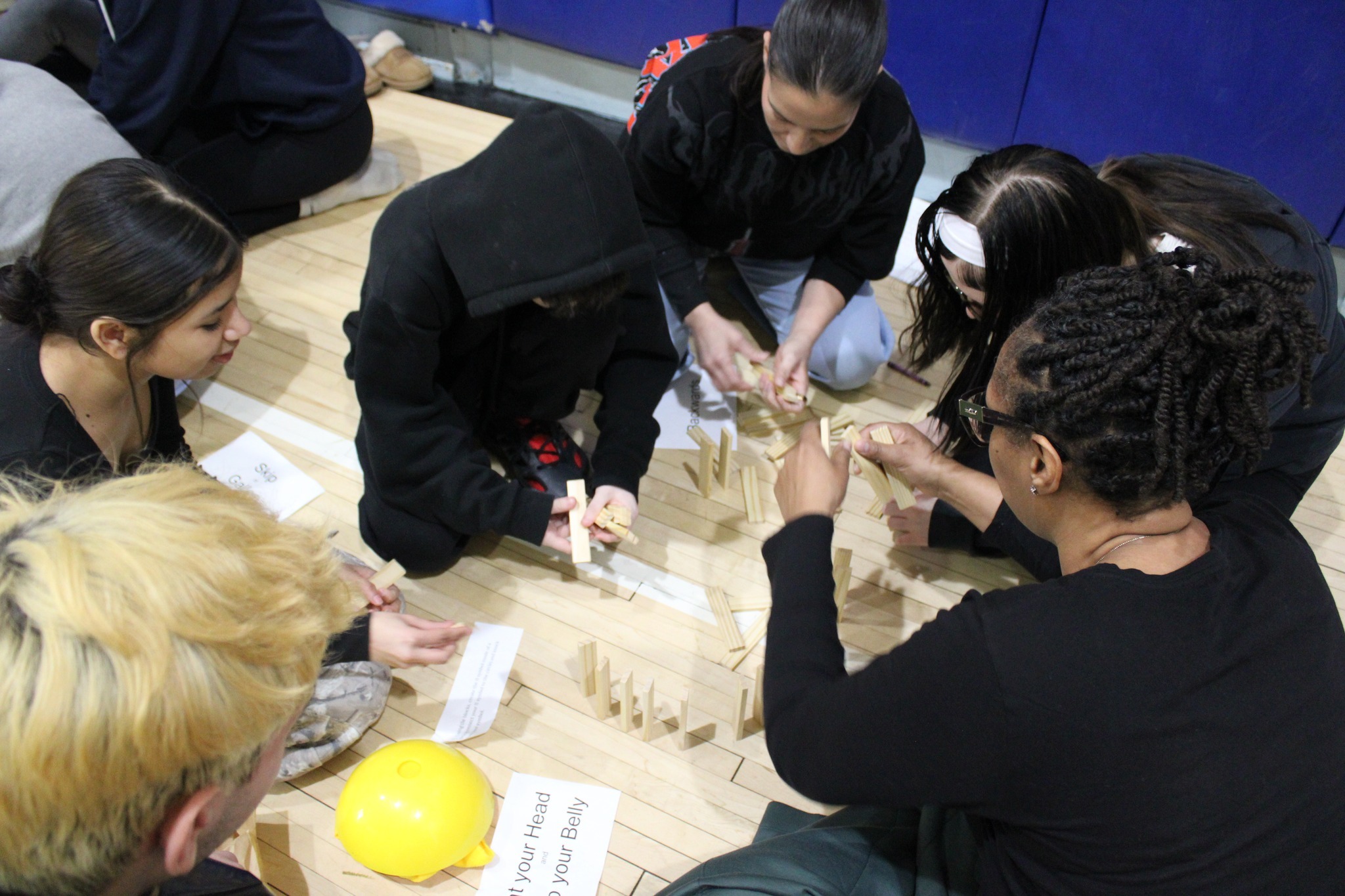 A group of five students working on a project on the floor.