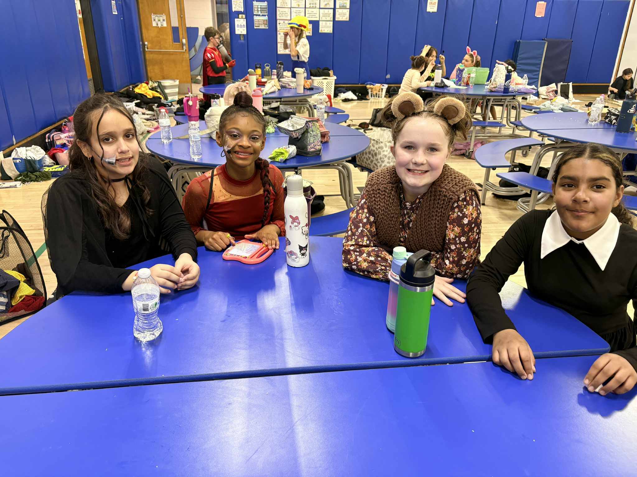 Four girls sitting at a table dressed for the play Shrek.