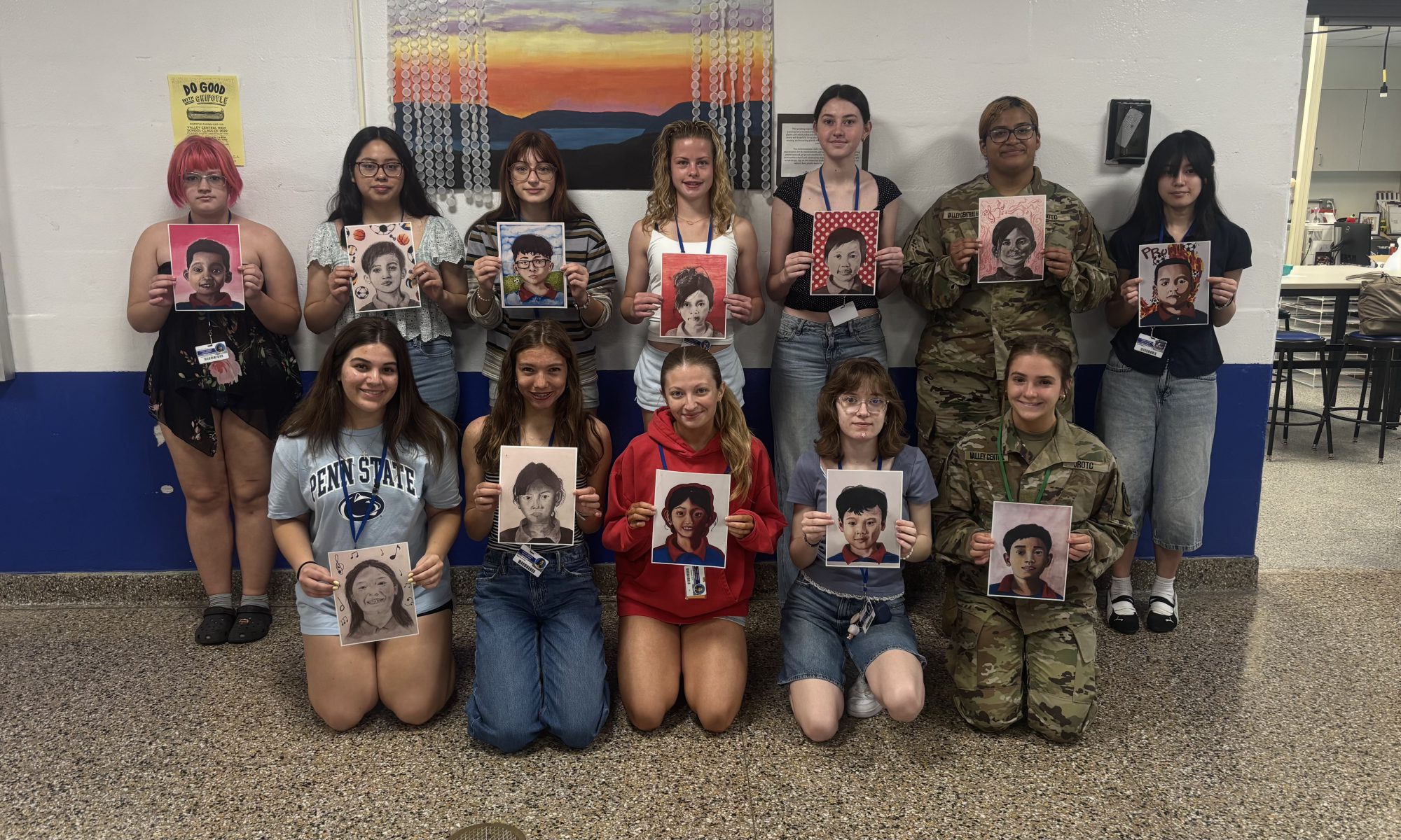 Students in The Advanced Drawing and Painting class at VCHS holding up portraits they created for students in Cambodia.