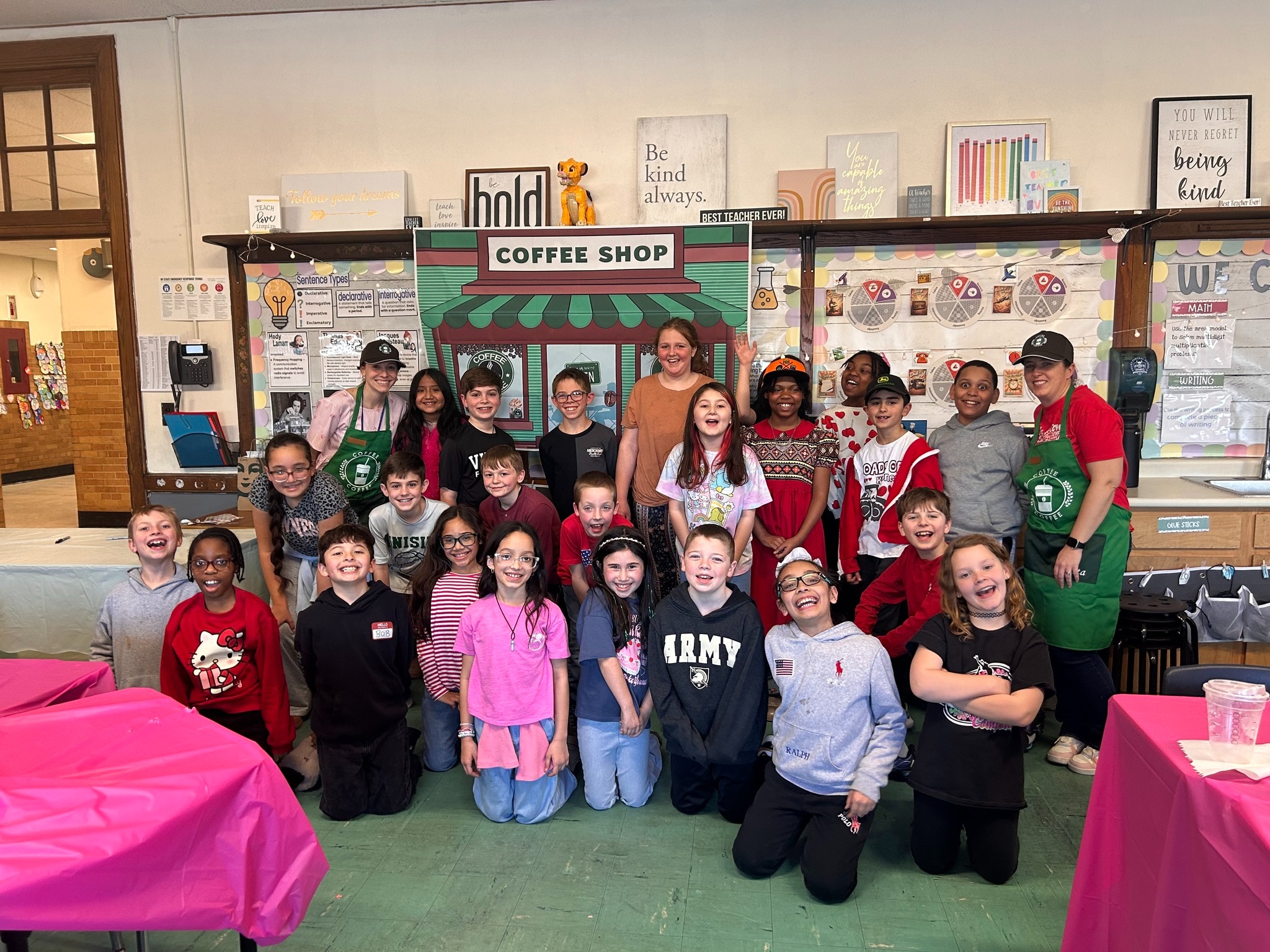 Group of students posed in front of a background made to look like a Starbucks coffee shop.