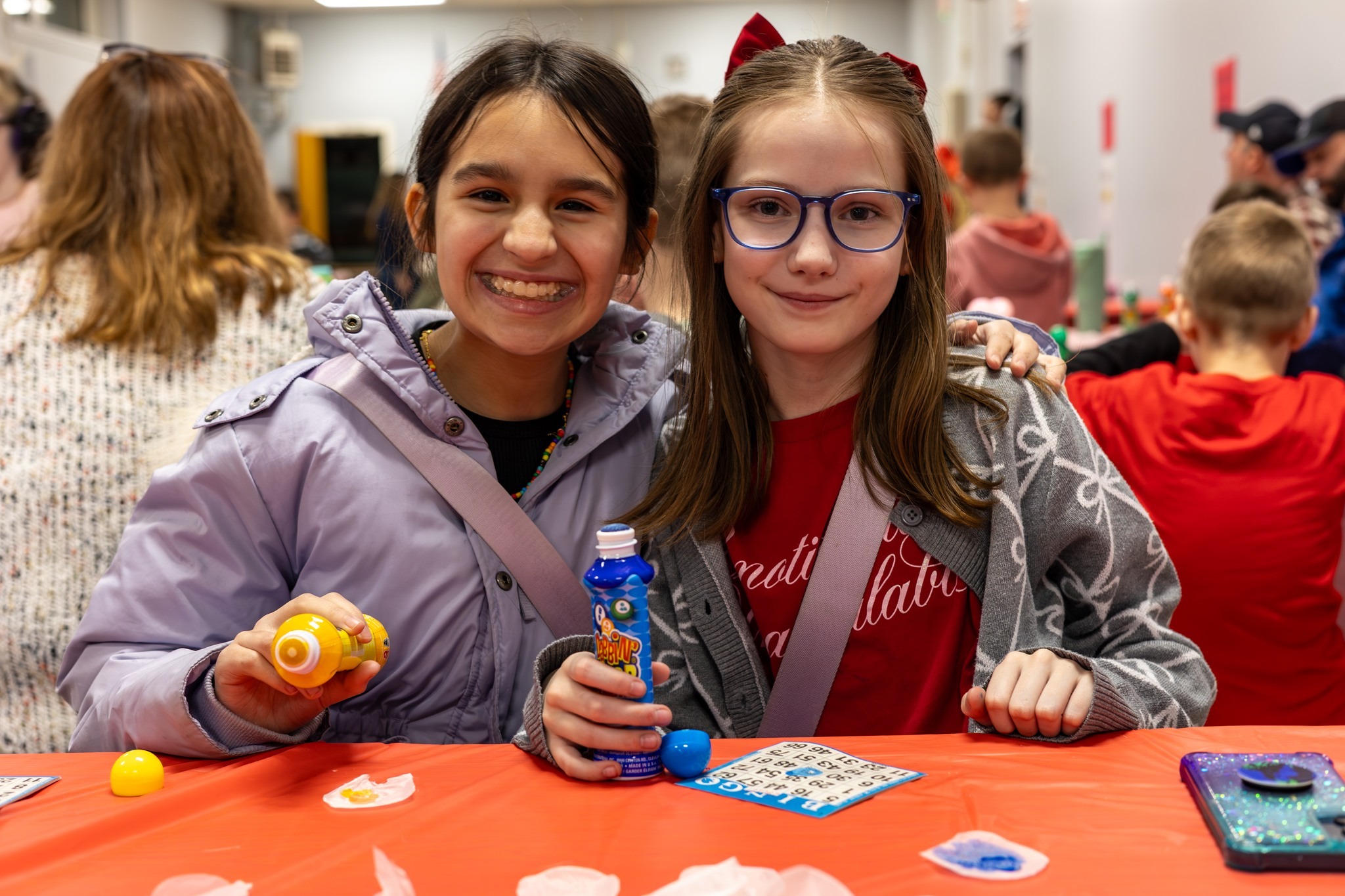 Two students posing together playing bingo.