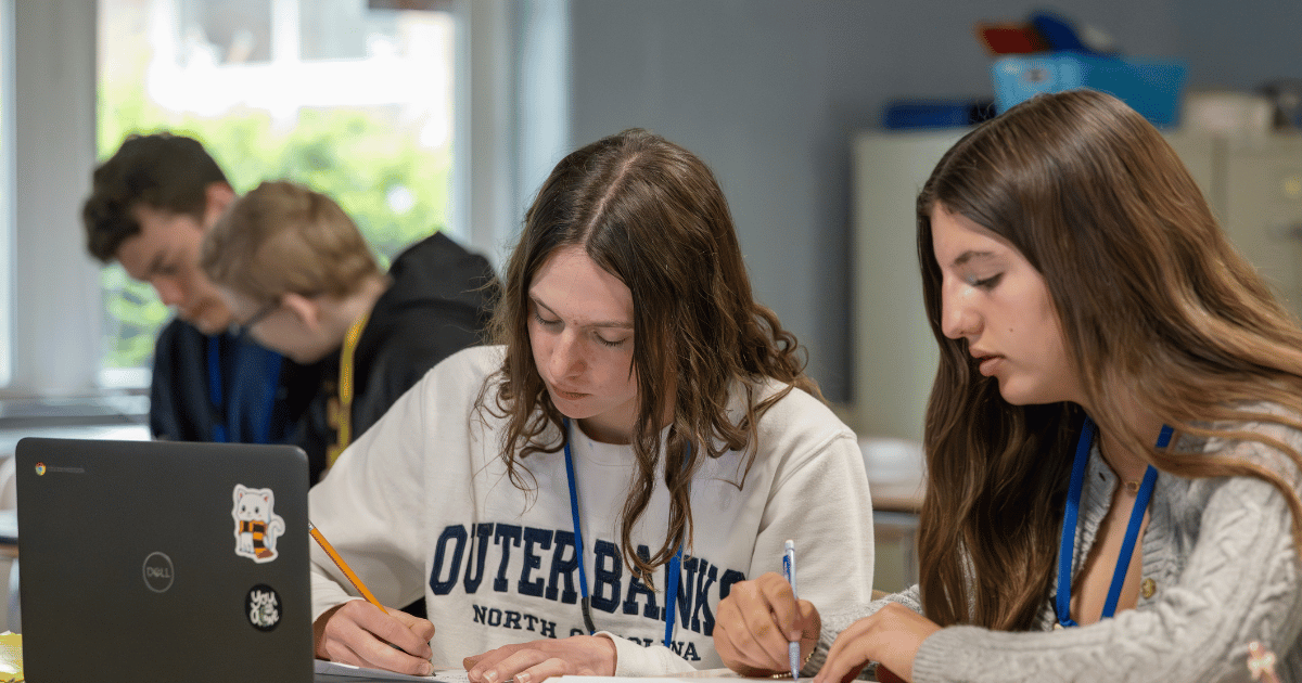 four students doing work in a classroom.