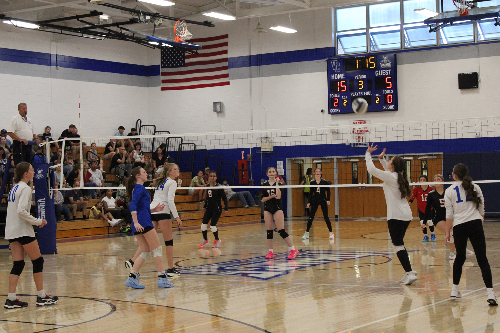 A volleyball player sets the ball for a teammate as opponents wait for the play
