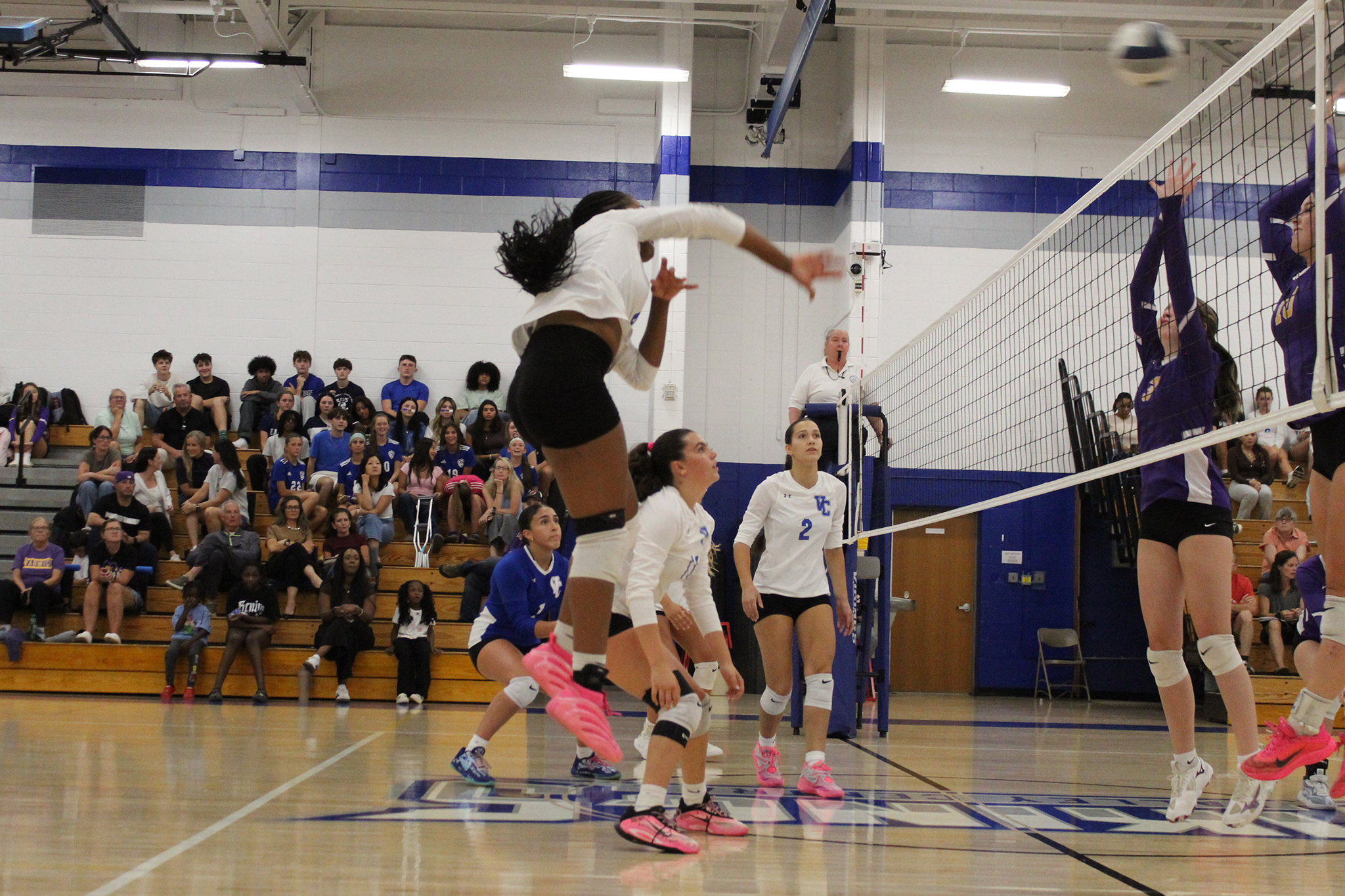 A Volleyball player hits the ball over the net as an opponent attempts to block