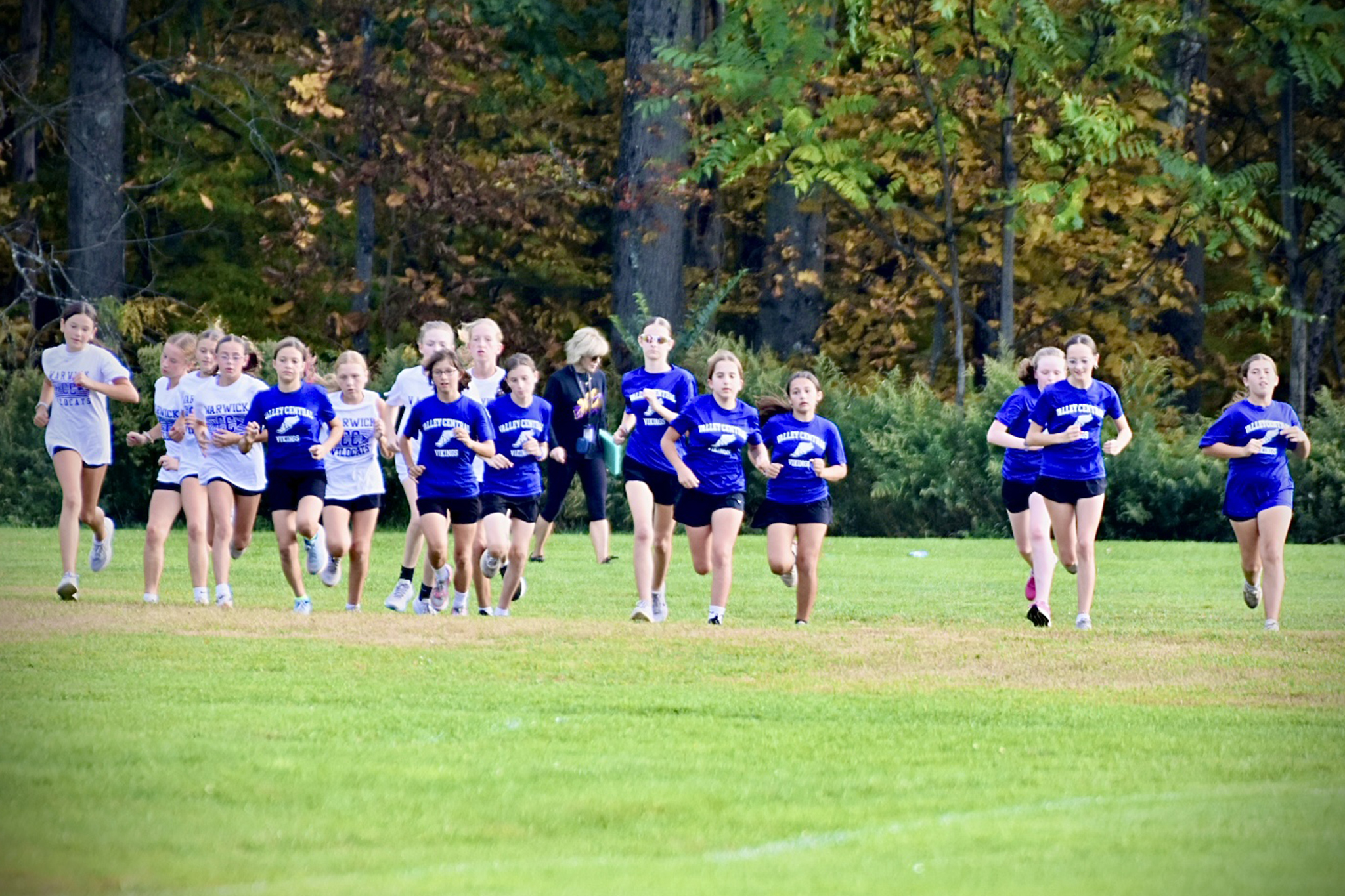 Girls cross country runners begin a race in a field