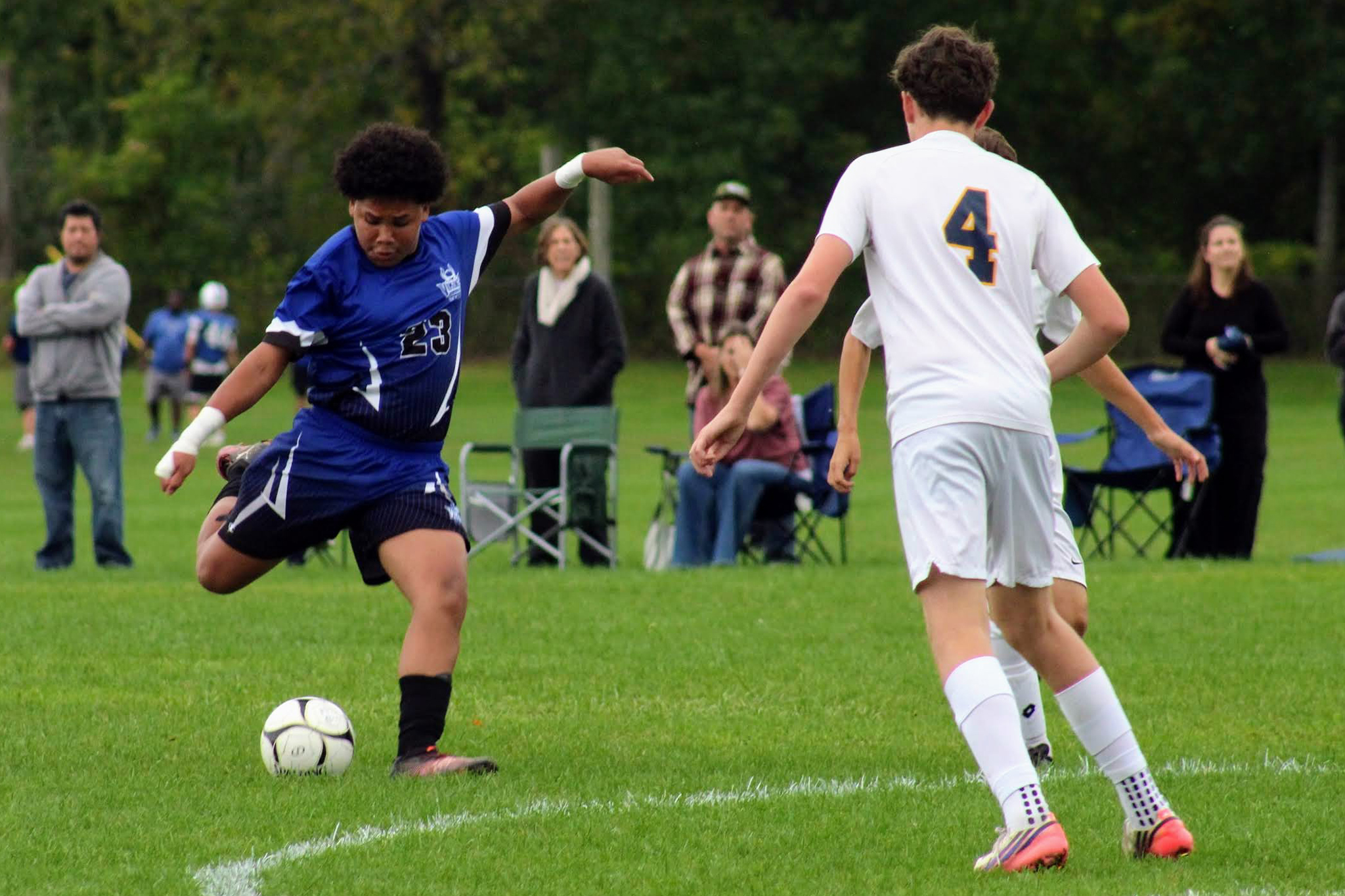 A soccer player prepares to kick a ball as an opposing player looks to defend